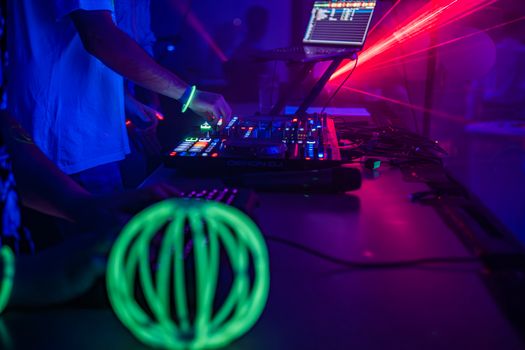 DJ mixing music at a nightclub with vibrant neon lights and professional sound equipment.