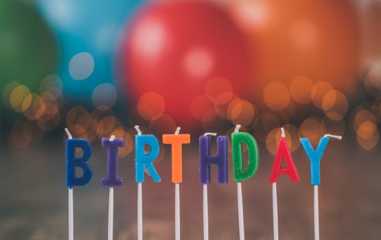 Vibrant birthday candles spelling "BIRTHDAY" against a festive, blurred background.