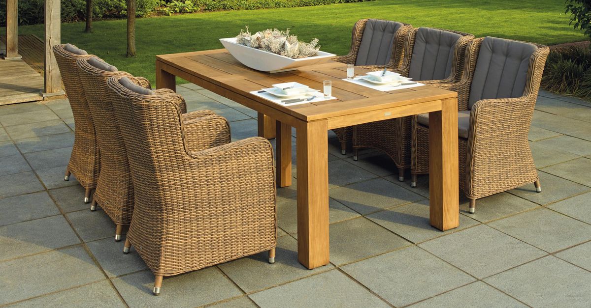 A serene outdoor patio set up with rattan chairs and a wooden table, perfect for relaxation.