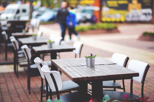 Stylish outdoor café setting with wooden tables and chairs, perfect for a sunny day lunch.