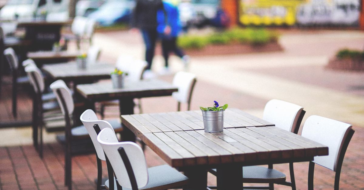 Stylish outdoor café setting with wooden tables and chairs, perfect for a sunny day lunch.
