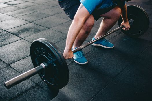 A man deadlifting a barbell indoors showcasing power, fitness, and dedication.