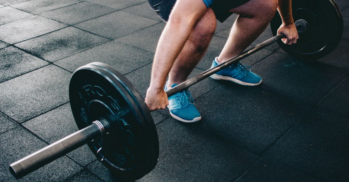 A man deadlifting a barbell indoors showcasing power, fitness, and dedication.