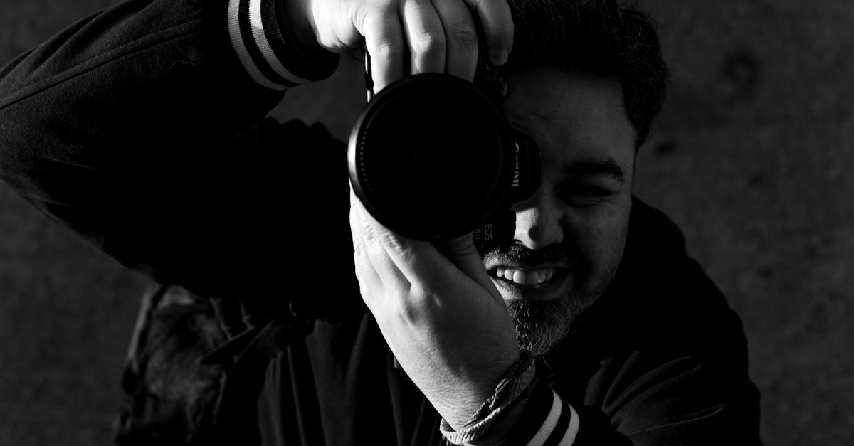 Dynamic black and white portrait capturing a photographer with a camera.