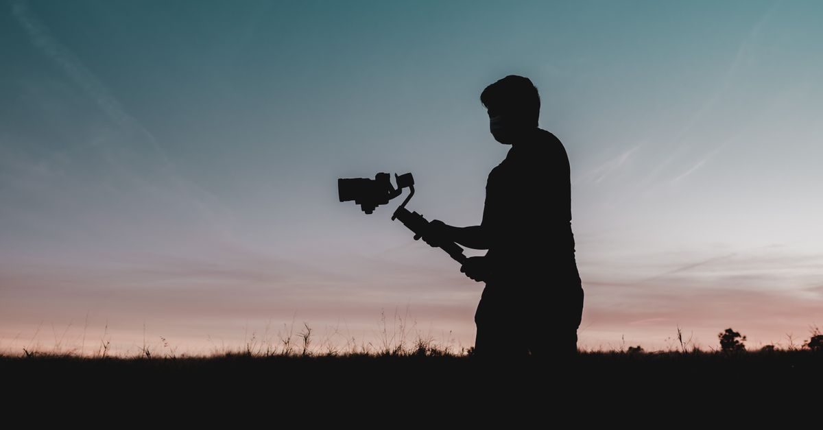 Silhouette of a man holding a camera while filming at sunset in Orlando.
