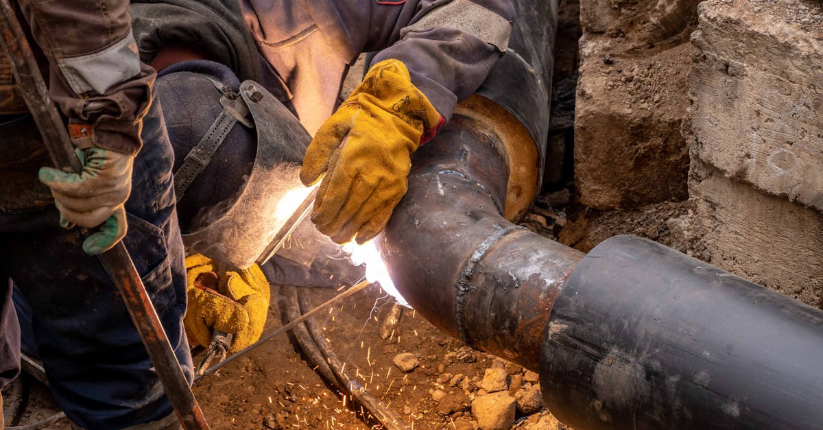 Close-up of a skilled worker welding steel pipes in an industrial setting, showcasing expertise and safety gear.