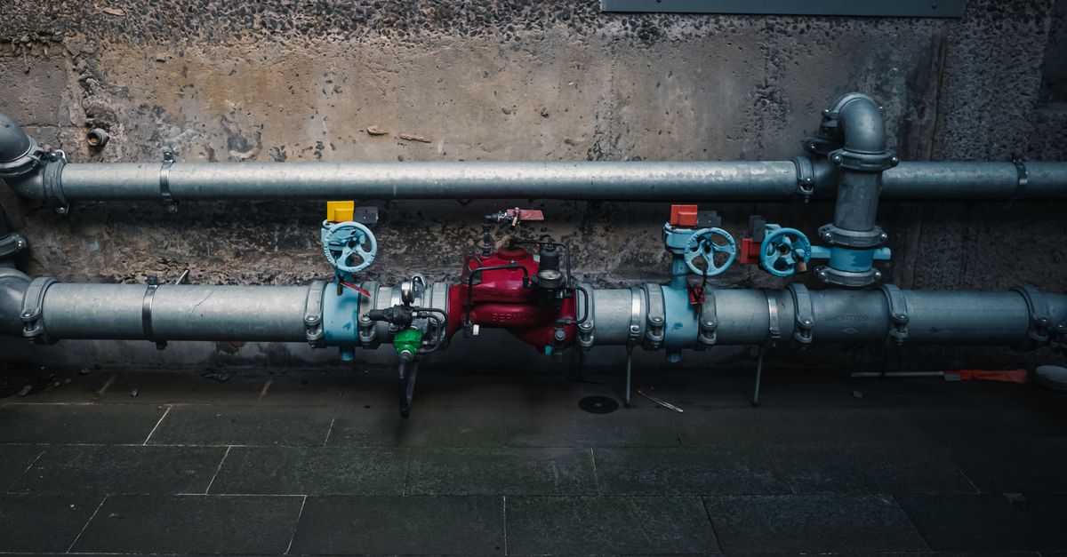A detailed view of industrial pipes with colorful valves on a textured wall.