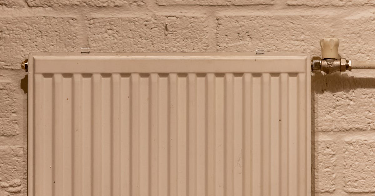 A clean white radiator mounted on a textured brick wall, indoors and well-lit.