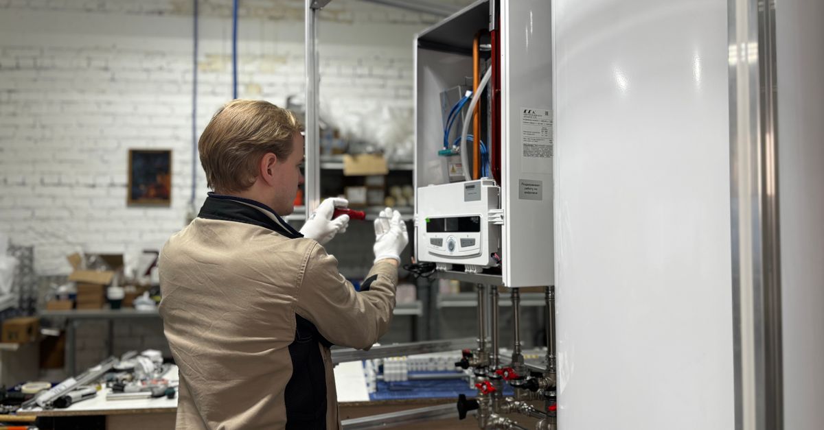 Technician inspects and repairs a heating system in an industrial workshop setting.