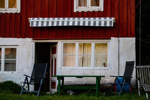 Charming rustic cabin with red and white facade and outdoor seating. Perfect for a cozy retreat.