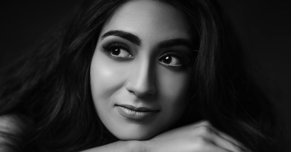 A captivating monochrome portrait of a woman with a thoughtful expression and arms crossed.