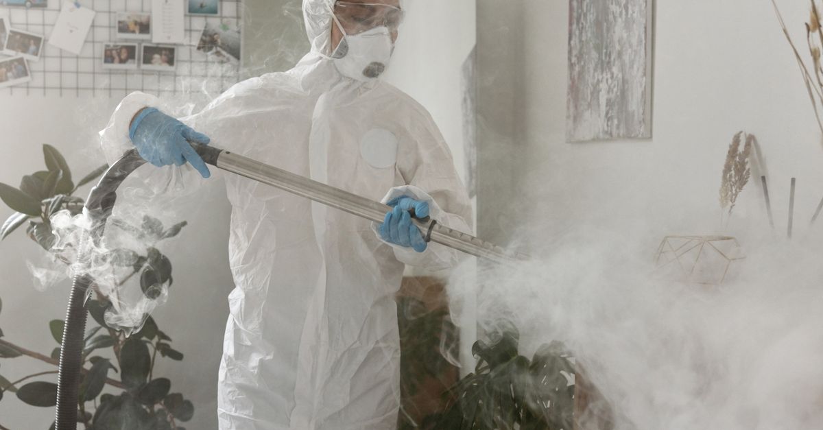 Person in PPE fumigating indoors for health safety during COVID-19.