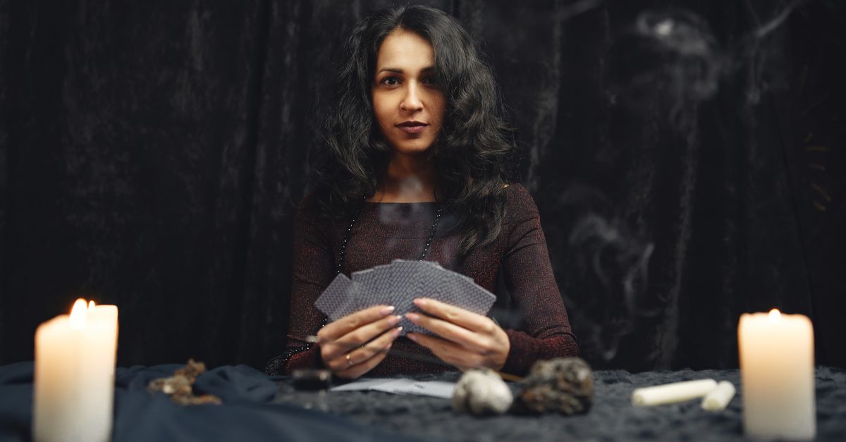 A mysterious woman holds tarot cards in a dimly lit setting, evoking a sense of mysticism and spirituality.