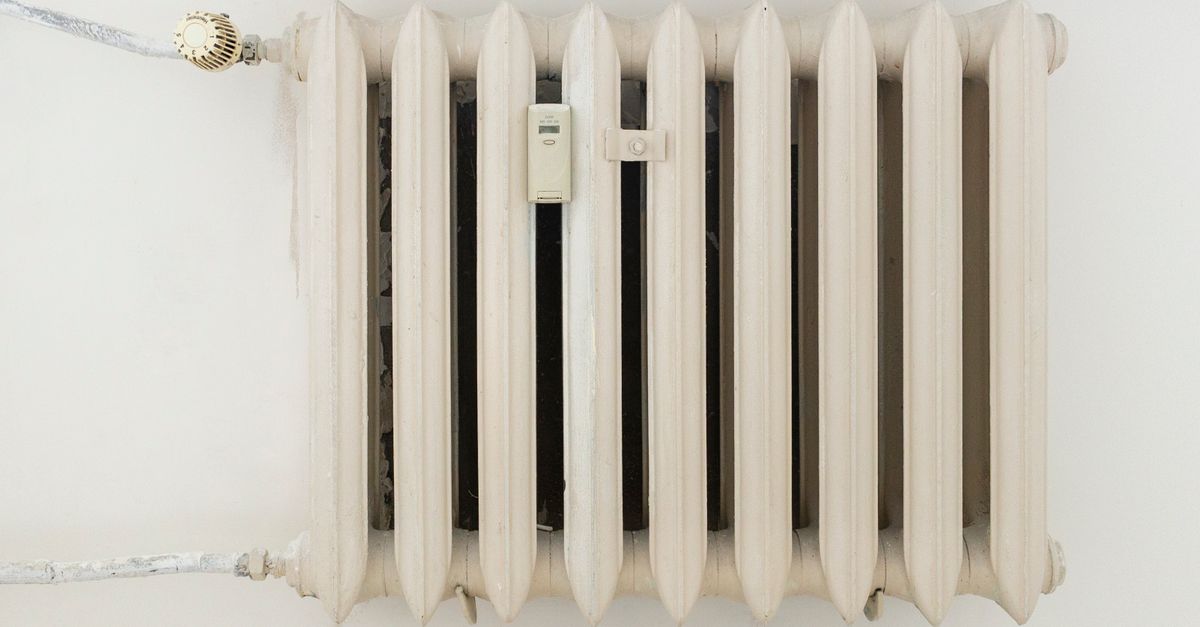 A classic white metal radiator on a plain wall, showcasing minimalist interior design.