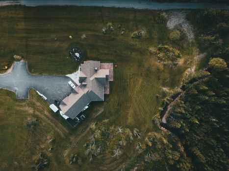 A stunning aerial shot of a suburban house surrounded by lush greenery and a driveway.
