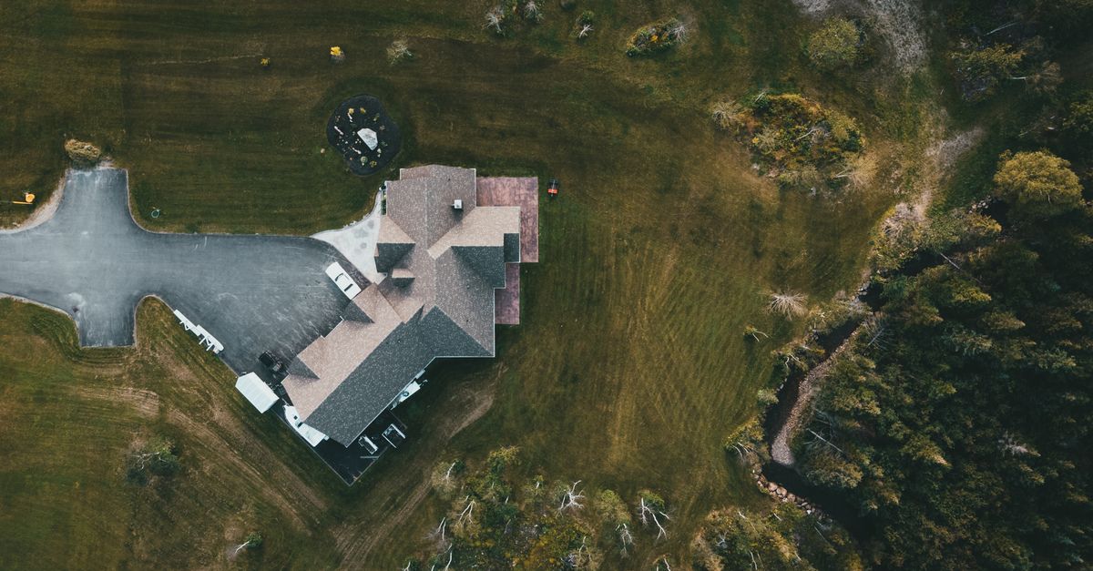 A stunning aerial shot of a suburban house surrounded by lush greenery and a driveway.