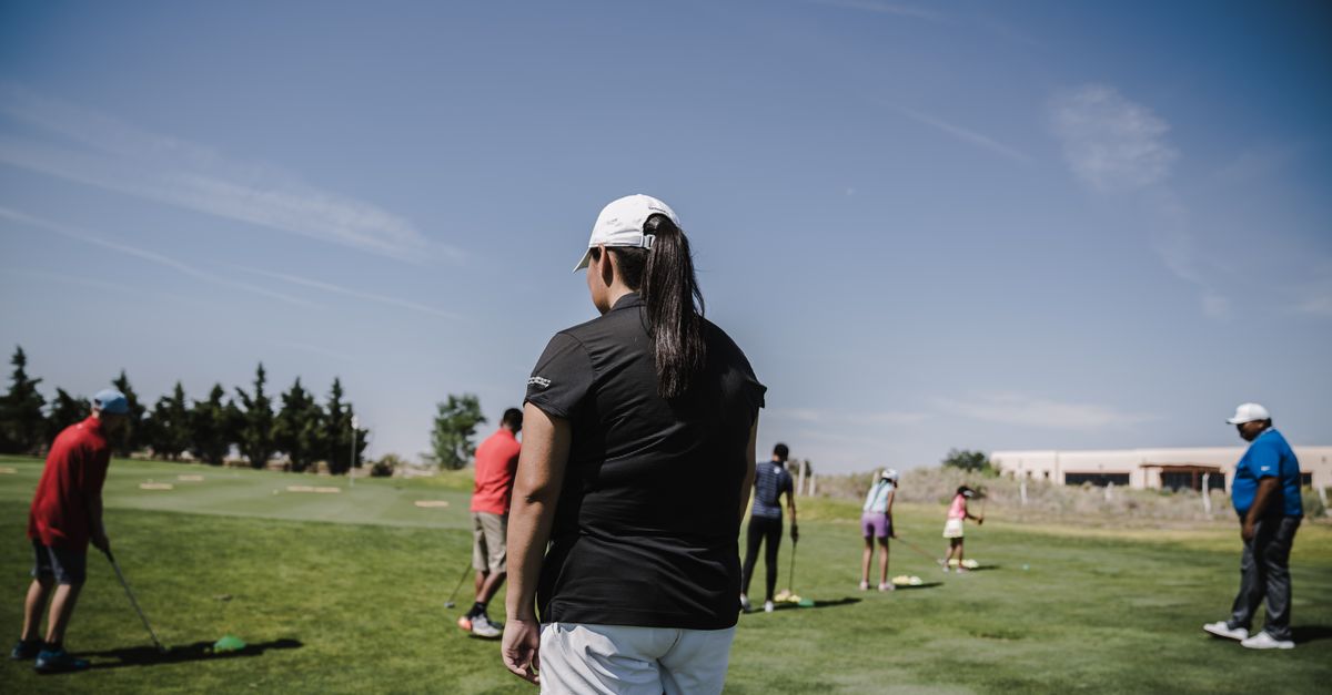 People enjoying a golf lesson on a bright day at the course.