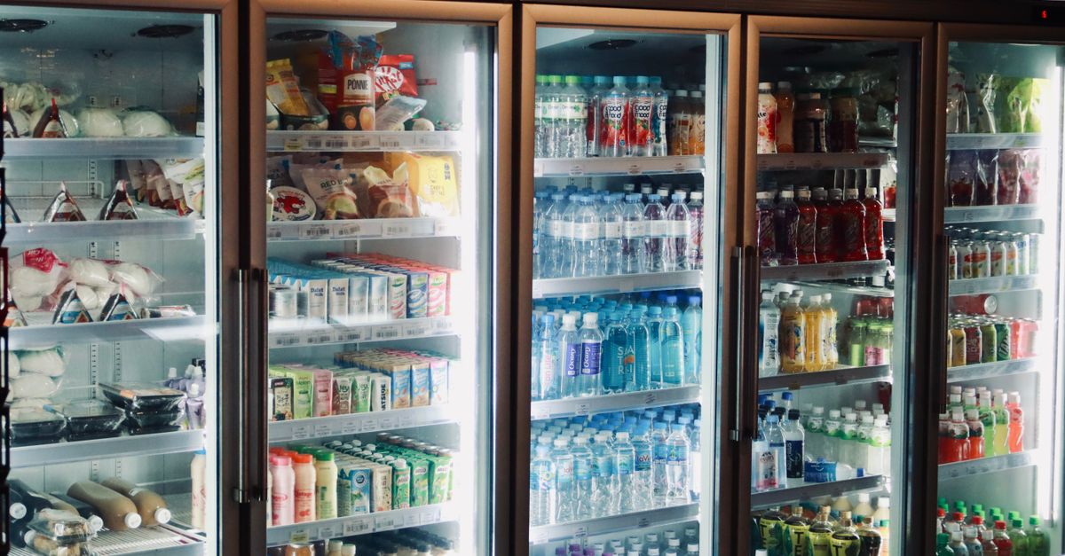 Refrigerator display with various beverages and snacks in a store environment.