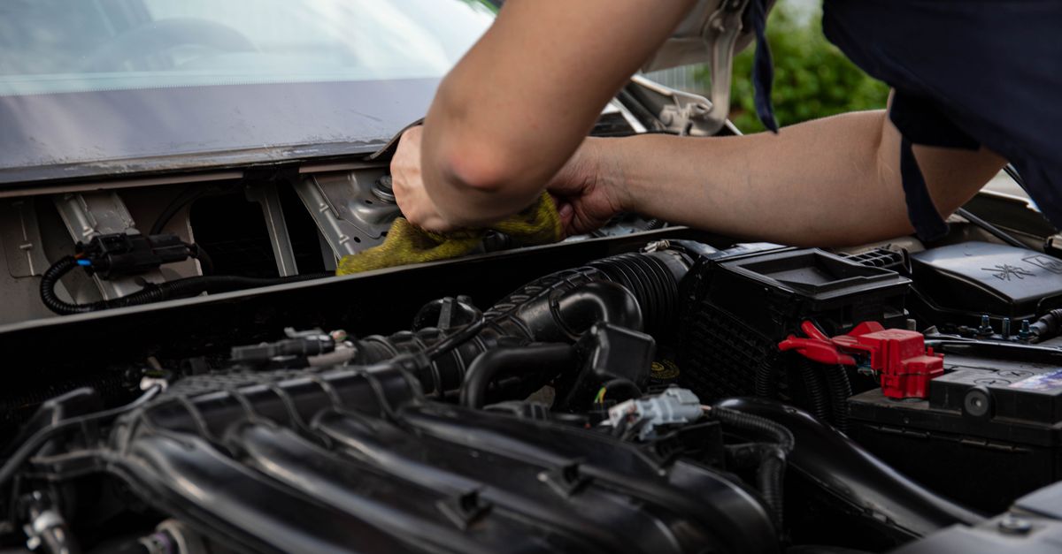 Close-up of a mechanic working on a car engine, showcasing hands and engine details.