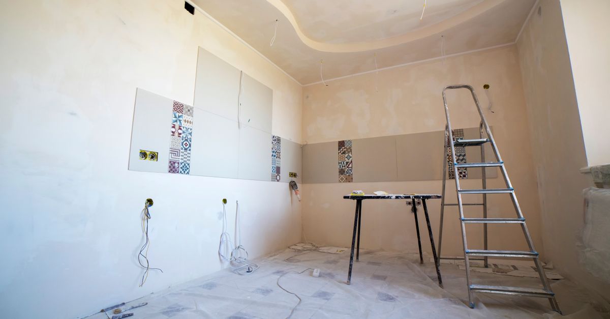 Interior view of a room under renovation with paint, tiles, and tools.