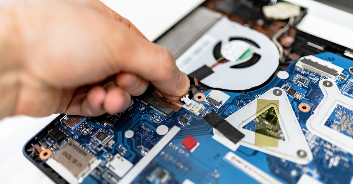 Close-up view of a hand fixing a computer motherboard showcasing technology and electronics repair.