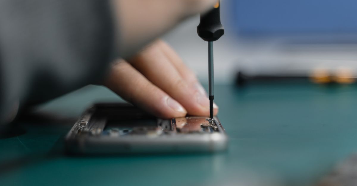 Detailed shot of smartphone repair with a screwdriver and hand close-up.