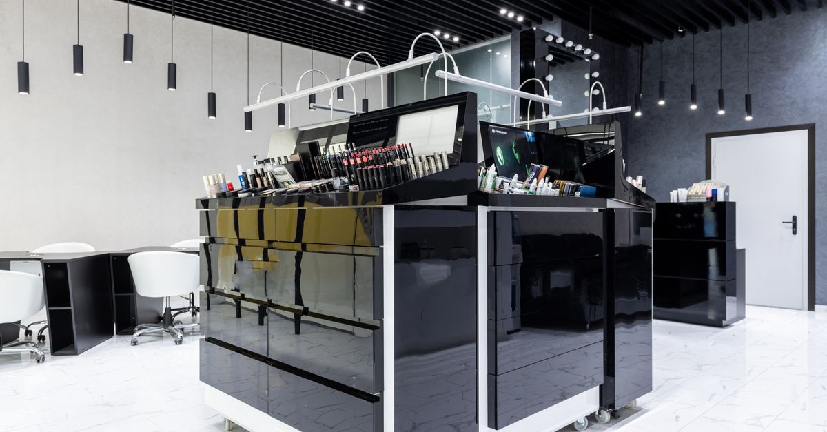 Sleek makeup store interior featuring black glossy cabinets, chairs, and ample lighting.
