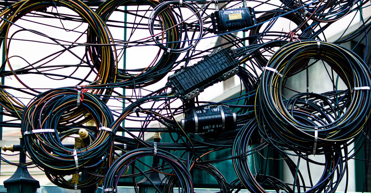Intricate network of tangled power and communication cables outdoors.