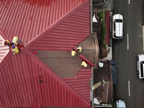 Aerial view of workers repairing a red metal roof in Quezon City, Philippines.