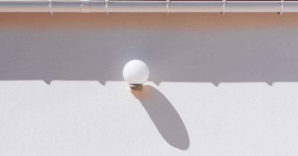 A minimalist outdoor setting showcasing a wall lamp casting a shadow beneath a red tiled roof.