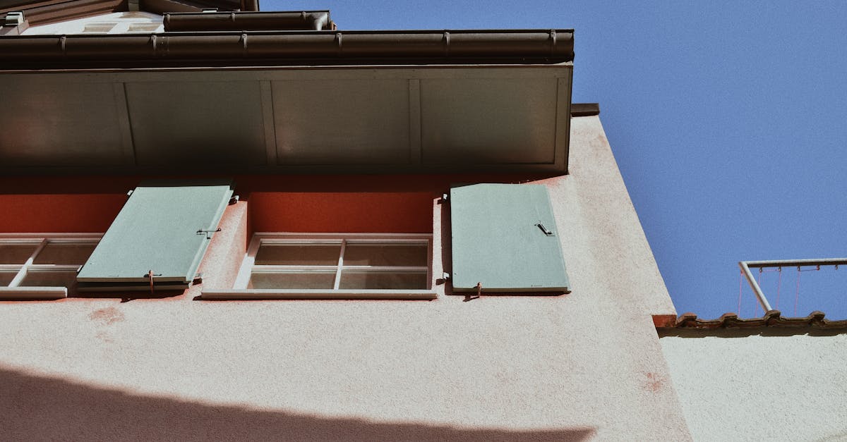 A close view of a building exterior showcasing distinctive green shutters against a pastel facade.
