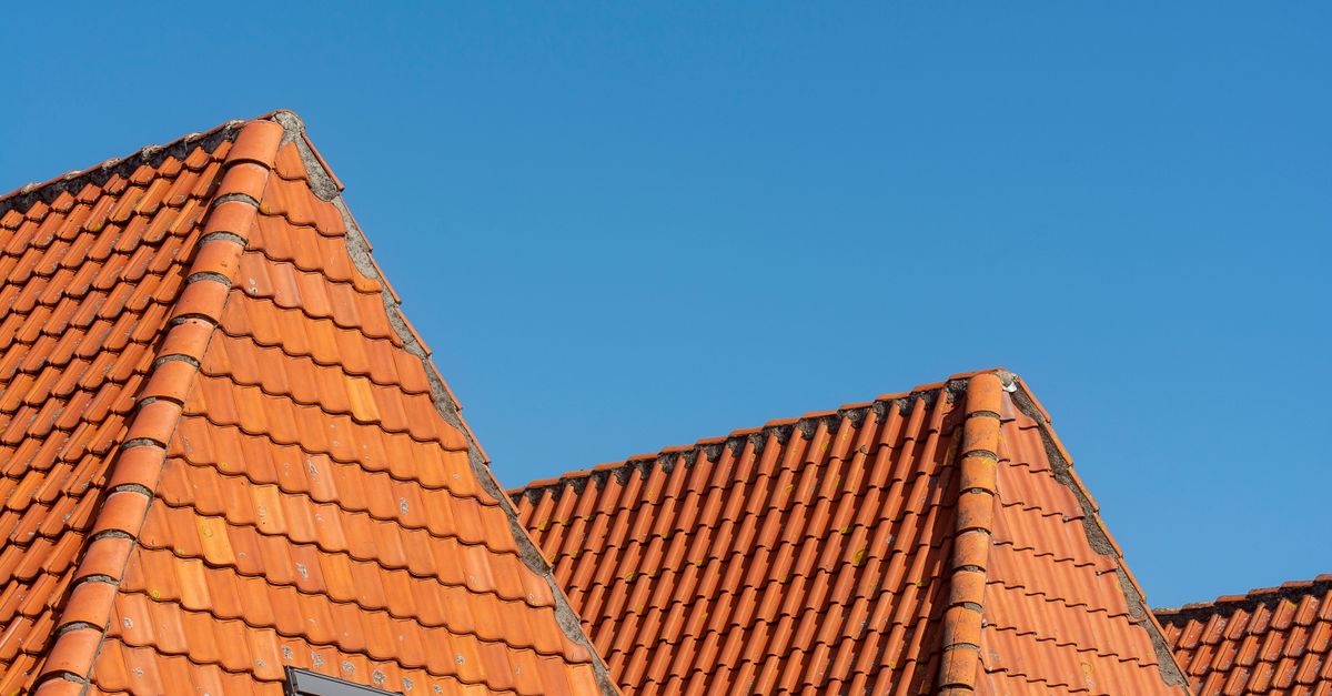 Close-up of red tiled roofs under a clear blue sky, showcasing architectural design.