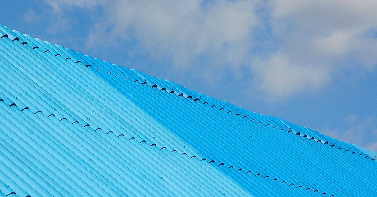 A bright blue corrugated roof shot from a low angle against a clear sky.