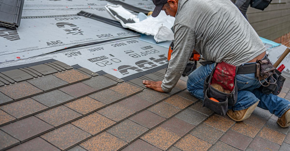 Skilled roofer installing asphalt shingles, ensuring quality home renovation.