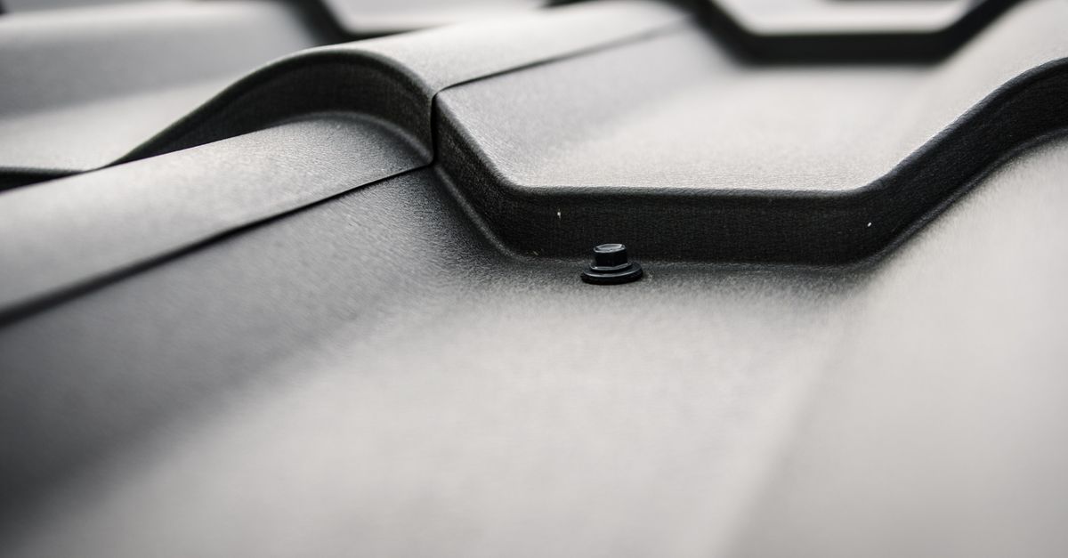 Detailed close-up of a black steel roof with prominent rivets and tiles.