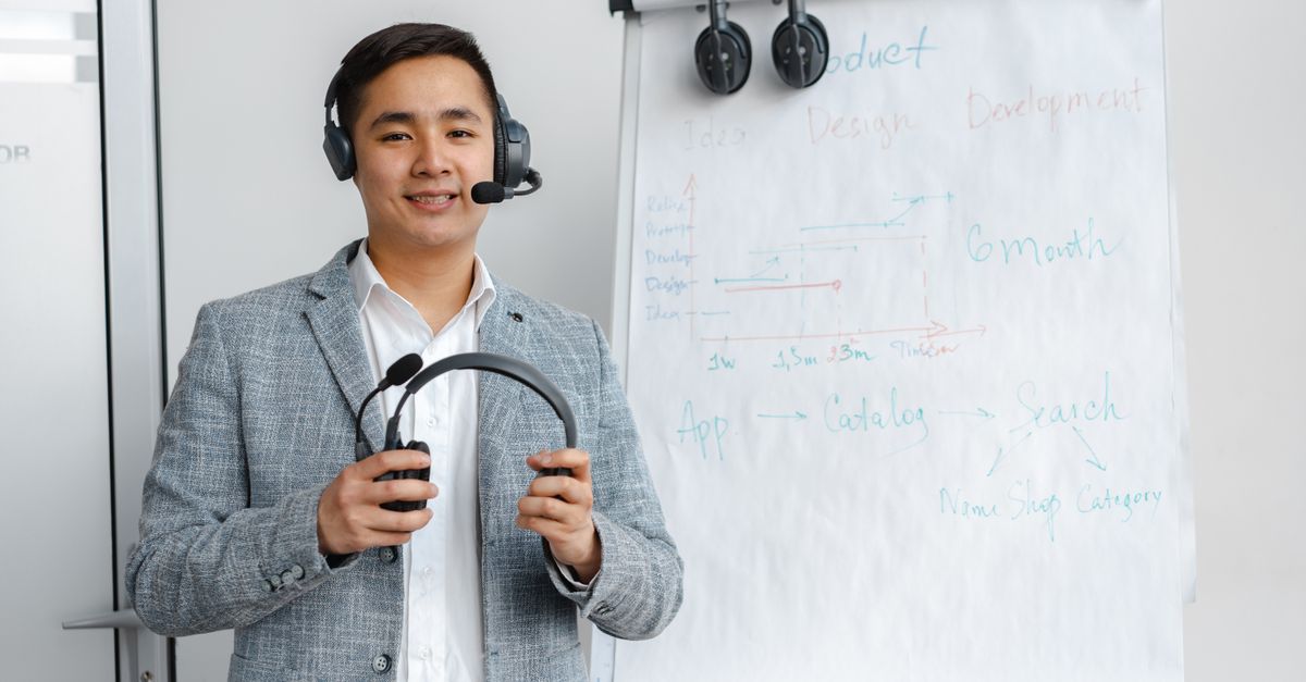 Friendly call center agent wearing headphones in an office setting with a flip chart presentation.
