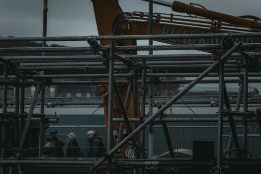 Scaffolding and machinery in an industrial setting with people in the background in Edinburgh, Scotland.
