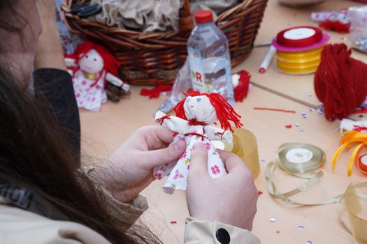 Person crafting a floral dress rag doll using colorful materials and threads.
