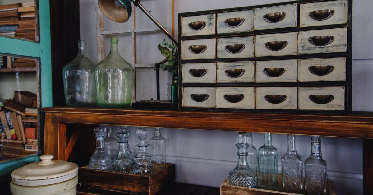 A rustic indoor scene featuring a vintage cabinet and glass bottles on a wooden shelf.