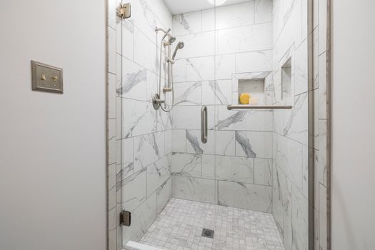 Elegant bathroom with white marble tiles and glass door, showcasing modern interior design.