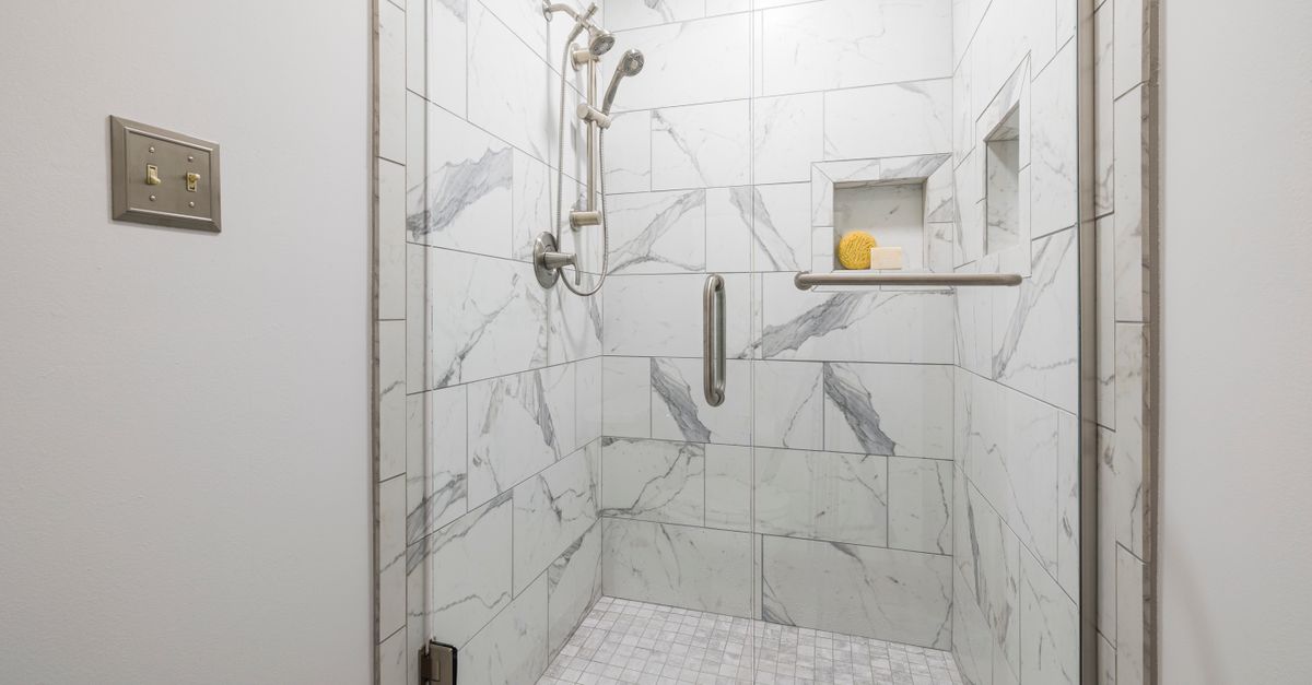 Elegant bathroom with white marble tiles and glass door, showcasing modern interior design.