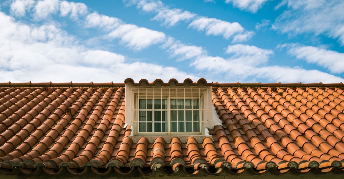 Close-up of a terracotta tiled roof with a skylight window in sunny Marbella, Spain.