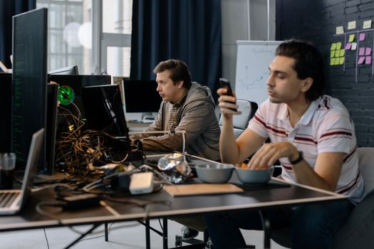 Two men working in a modern office setup, focused on technology and collaboration.