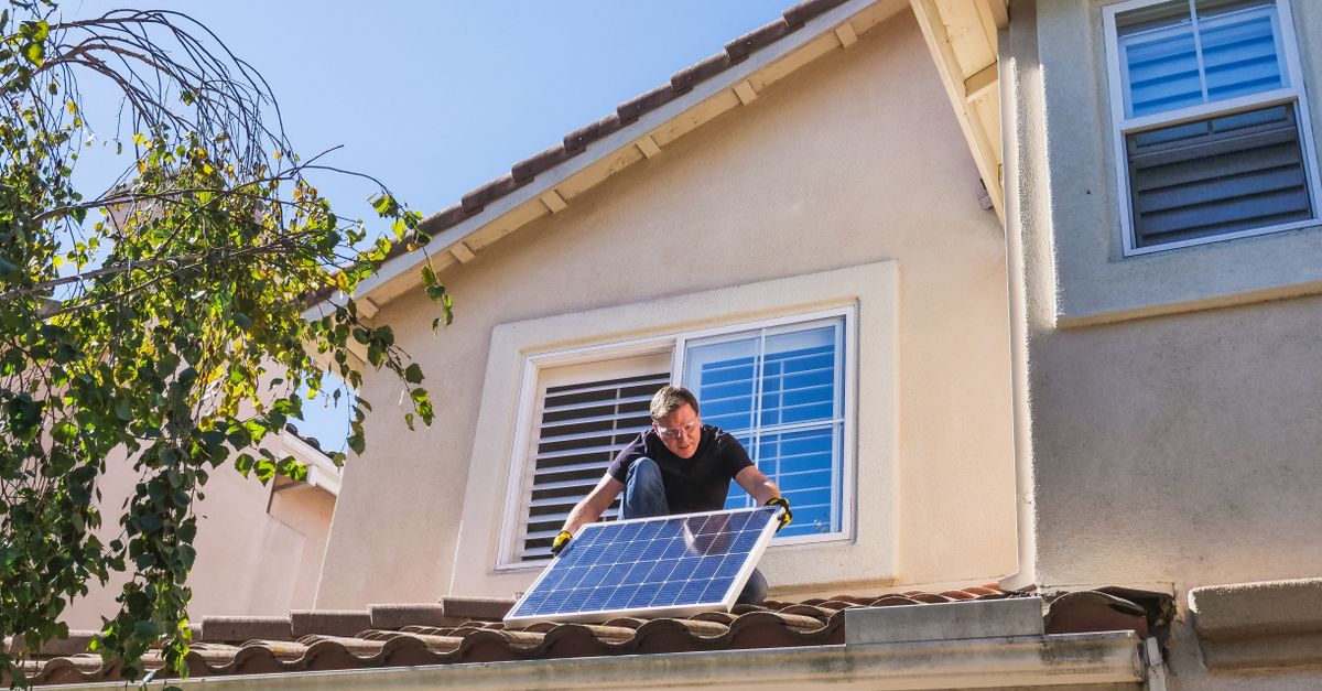 Solar technician installing photovoltaic panels on a sunny rooftop.