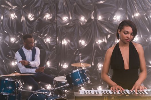A jazz band featuring a pianist and drummer performing on stage with moody lighting.