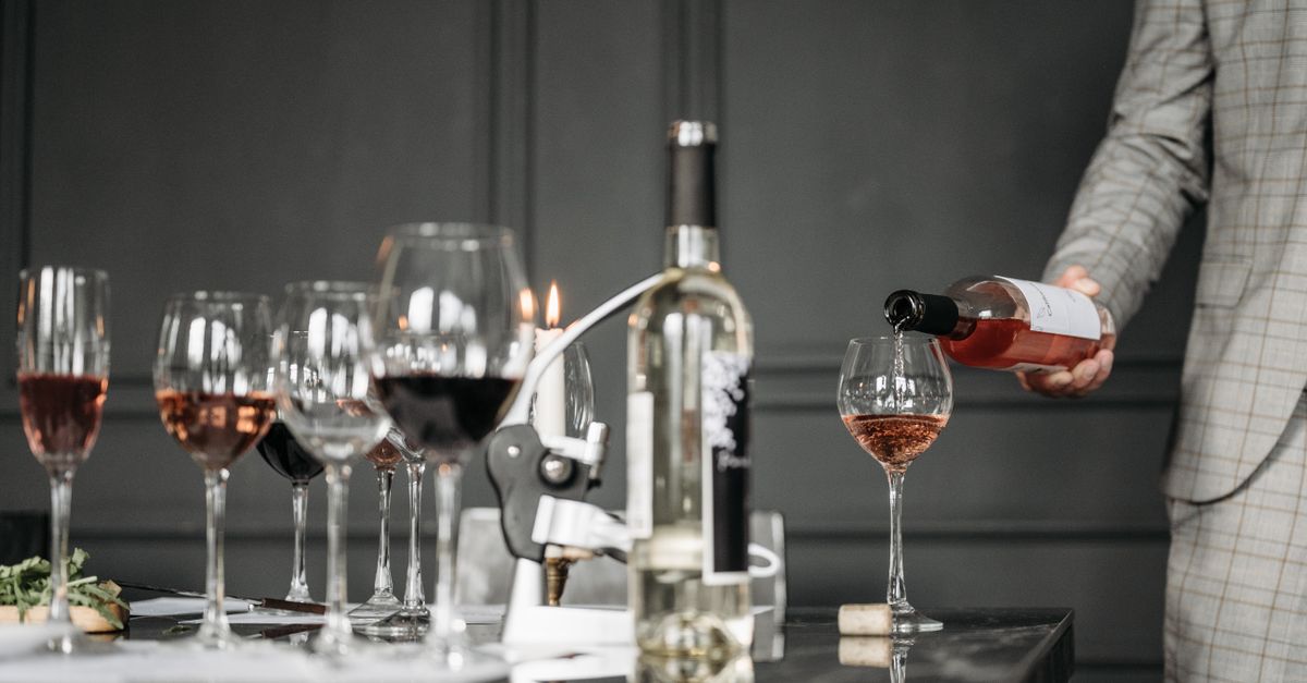 Close-up of a wine tasting session with a sommelier pouring rosé into a glass.