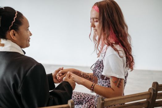A pastor holds hands with a woman in a candid moment of connection and faith.