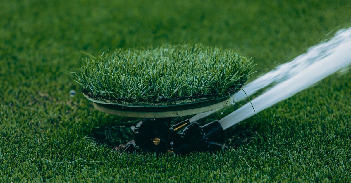Close-up of an automatic sprinkler watering a lush green lawn, showcasing irrigation system.
