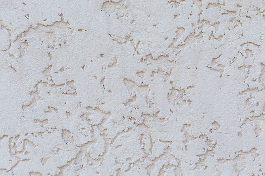 Textured background of white plaster wall with small holes on surface of building