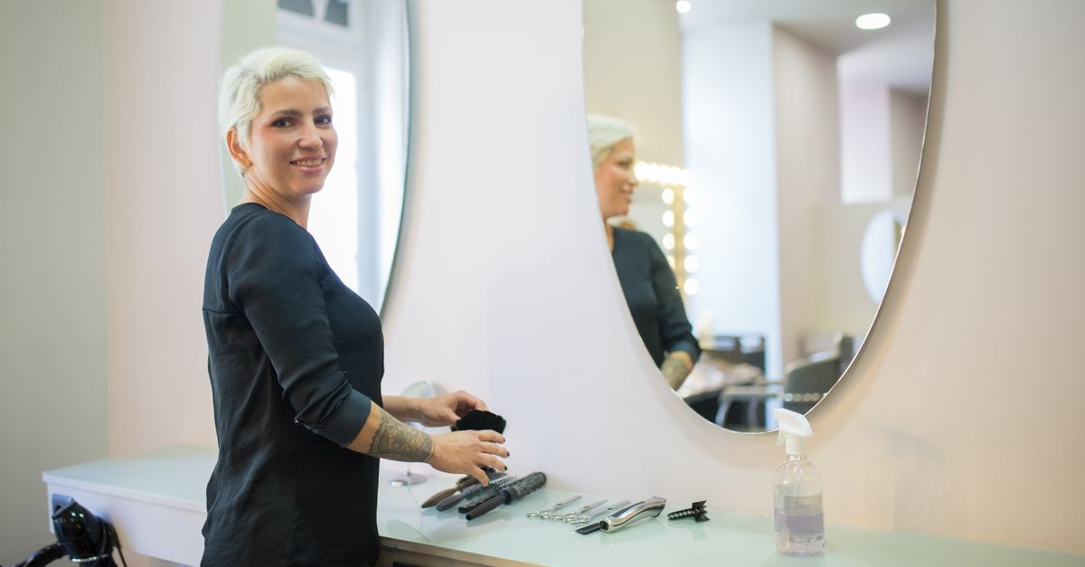 A hair stylist in a modern salon in Portugal with tools and a mirror.